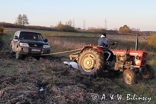 samochód terenowy zakopany w błocie, fachowa pomoc traktora niezbędna